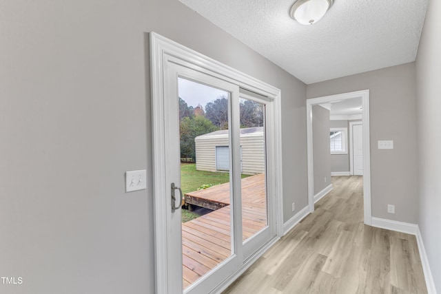 doorway to outside featuring light hardwood / wood-style flooring and a textured ceiling