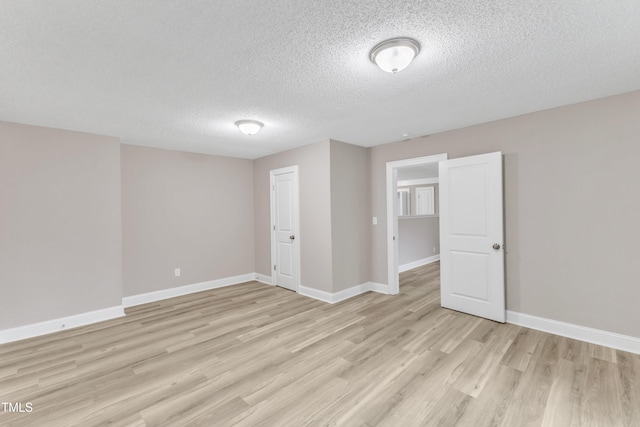 unfurnished room featuring a textured ceiling and light hardwood / wood-style floors