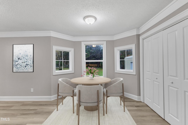 dining room with ornamental molding, a textured ceiling, and light hardwood / wood-style floors