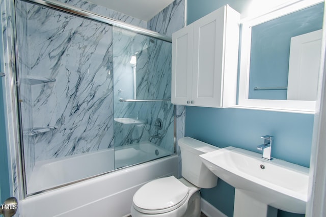 bathroom with combined bath / shower with glass door, toilet, and a sink