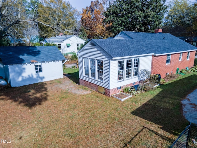 back of house with an outbuilding, roof with shingles, a chimney, crawl space, and a lawn