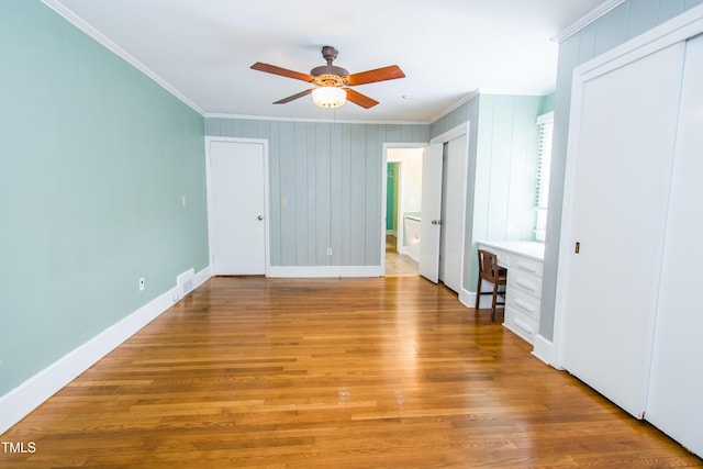 unfurnished bedroom with built in study area, light wood-style floors, and ornamental molding