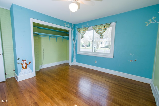 unfurnished bedroom featuring a closet, wood-type flooring, baseboards, and a ceiling fan