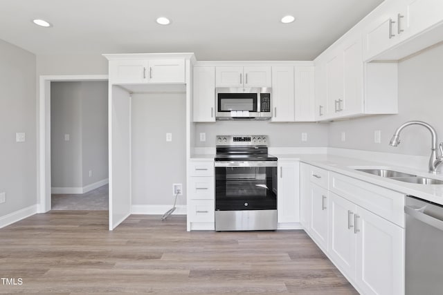 kitchen featuring light wood-style flooring, white cabinets, stainless steel appliances, and a sink