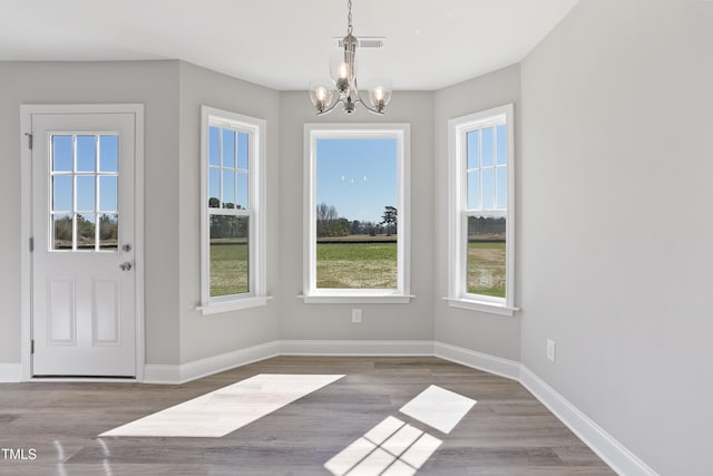 entrance foyer with a notable chandelier, visible vents, baseboards, and wood finished floors