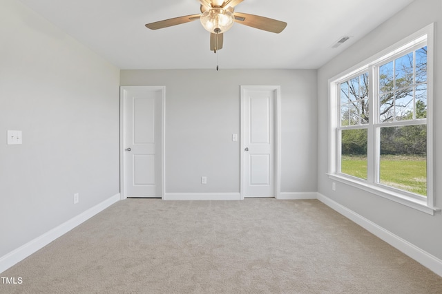 unfurnished bedroom with light carpet, visible vents, a ceiling fan, and baseboards