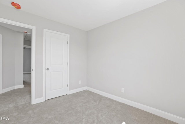 unfurnished bedroom featuring baseboards, attic access, and carpet flooring