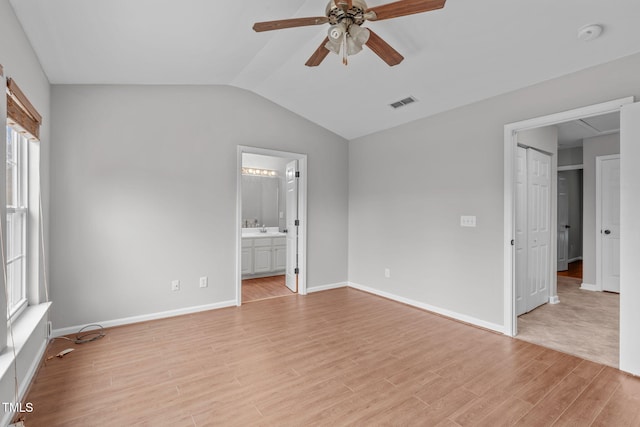 unfurnished bedroom with connected bathroom, light hardwood / wood-style flooring, multiple windows, and ceiling fan