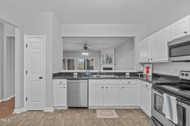 kitchen with stainless steel appliances, ceiling fan, sink, dark stone countertops, and white cabinets