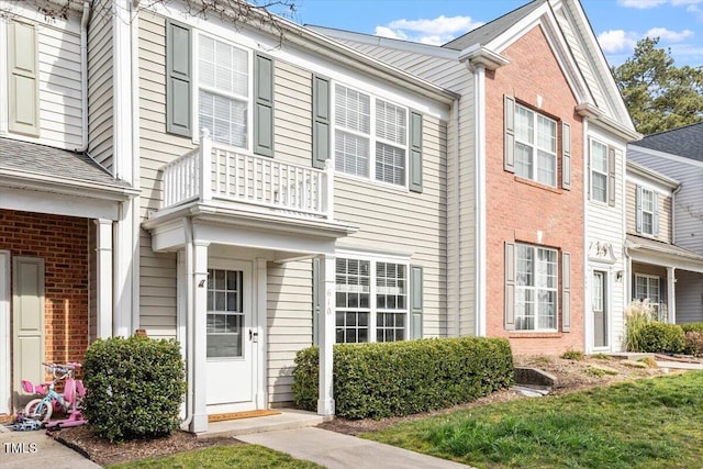 view of front of house with brick siding and a balcony