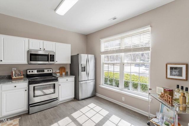 kitchen with appliances with stainless steel finishes, white cabinetry, and visible vents