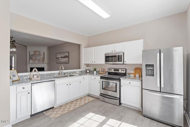 kitchen featuring stainless steel appliances, light wood-style floors, white cabinets, and a sink