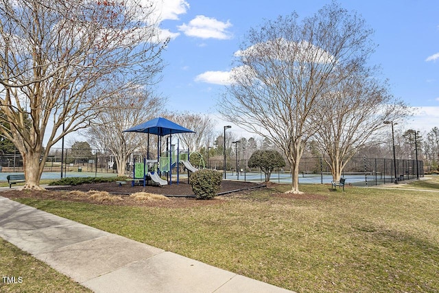 community play area with a tennis court, fence, and a yard