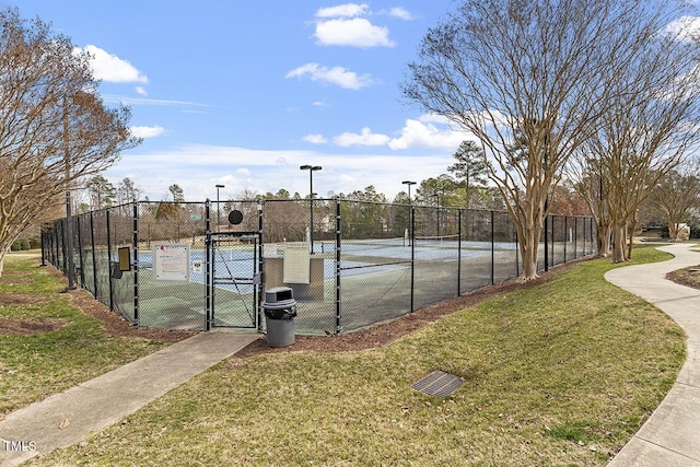 view of sport court featuring a gate, fence, and a yard