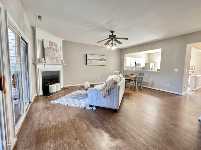 living room with a fireplace with flush hearth, wood finished floors, visible vents, and a healthy amount of sunlight