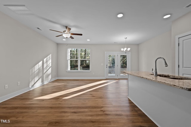 kitchen with pendant lighting, sink, light stone counters, and dark wood-type flooring