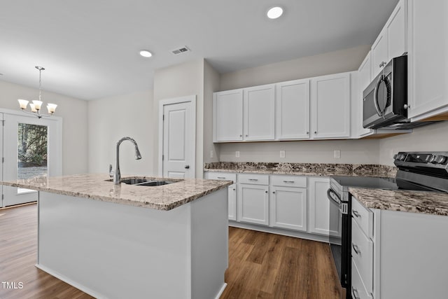 kitchen featuring electric range oven, pendant lighting, sink, white cabinets, and a center island with sink