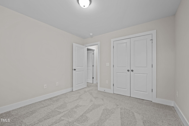 unfurnished bedroom with light colored carpet and a closet