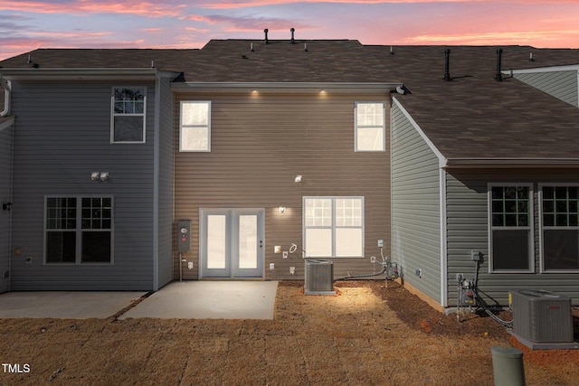 back house at dusk with central AC unit and a patio