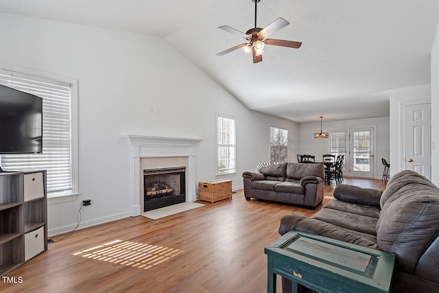 living room featuring plenty of natural light, ceiling fan, wood-type flooring, and lofted ceiling