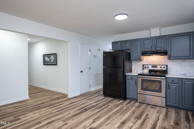 kitchen featuring backsplash, electric range, black refrigerator, and wood-type flooring