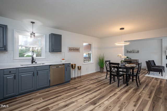 kitchen featuring dishwasher, sink, dark wood-type flooring, tasteful backsplash, and decorative light fixtures