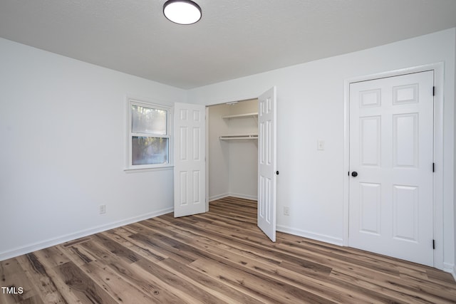 unfurnished bedroom with dark hardwood / wood-style flooring, a textured ceiling, and a closet