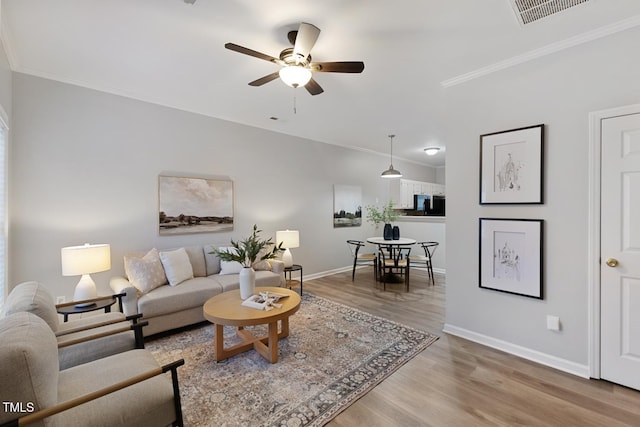 living room with hardwood / wood-style floors, ceiling fan, and crown molding