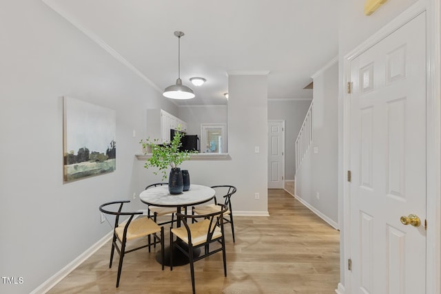 dining space featuring crown molding and light hardwood / wood-style floors