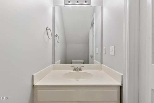 bathroom with vanity, toilet, and lofted ceiling