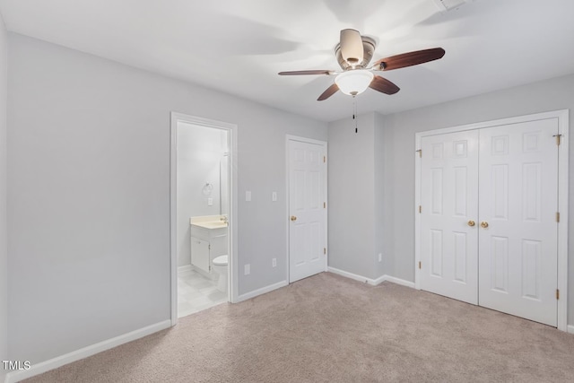 unfurnished bedroom featuring ceiling fan, a closet, light carpet, and ensuite bath