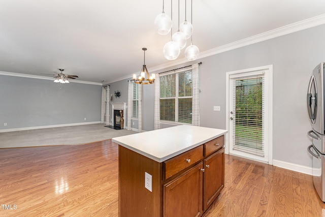 kitchen featuring pendant lighting, a center island, light hardwood / wood-style flooring, ornamental molding, and ceiling fan with notable chandelier