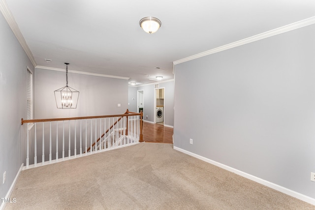 carpeted spare room featuring an inviting chandelier, ornamental molding, and washer / clothes dryer