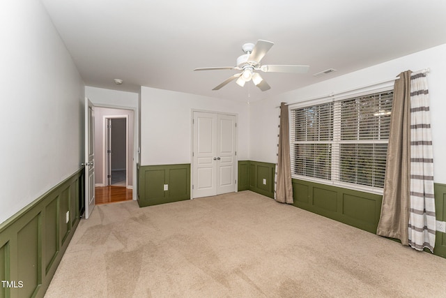 unfurnished bedroom featuring ceiling fan, a closet, and light colored carpet