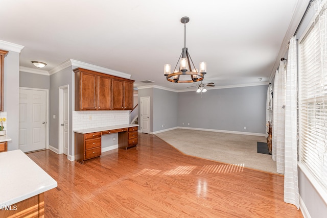 kitchen with crown molding, ceiling fan with notable chandelier, tasteful backsplash, and pendant lighting