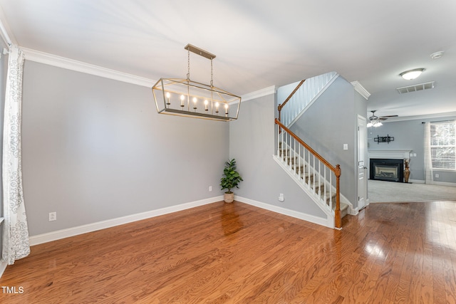 interior space featuring crown molding, ceiling fan with notable chandelier, and hardwood / wood-style floors