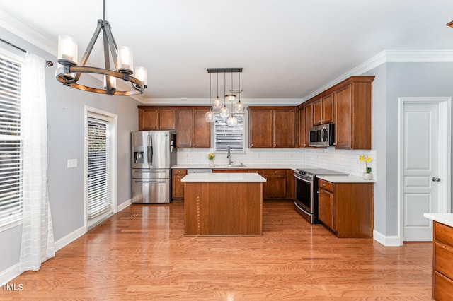 kitchen with appliances with stainless steel finishes, backsplash, a kitchen island, pendant lighting, and sink