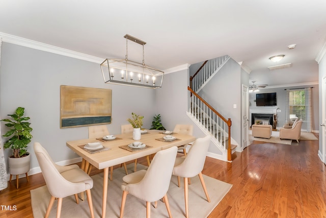 dining room featuring hardwood / wood-style flooring, ornamental molding, and ceiling fan with notable chandelier