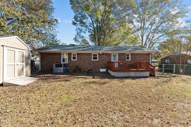 rear view of house with cooling unit, a yard, a storage unit, and a deck