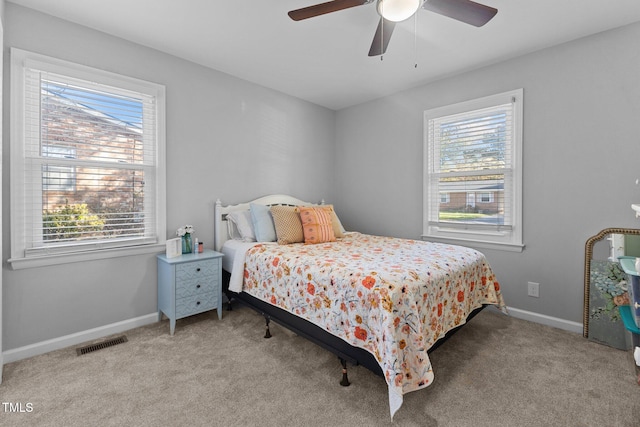 bedroom featuring ceiling fan, light carpet, and multiple windows