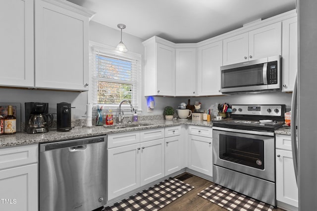 kitchen with light stone countertops, sink, dark hardwood / wood-style flooring, white cabinets, and appliances with stainless steel finishes