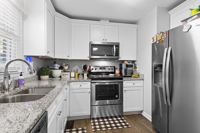 kitchen featuring white cabinets, sink, dark hardwood / wood-style floors, appliances with stainless steel finishes, and light stone counters