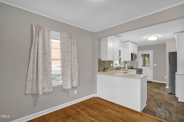 kitchen featuring dark wood-type flooring, stainless steel appliances, tasteful backsplash, kitchen peninsula, and white cabinets