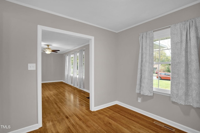 spare room with wood-type flooring, crown molding, and a healthy amount of sunlight