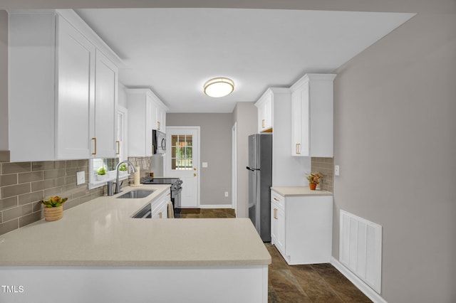 kitchen with sink, stainless steel appliances, tasteful backsplash, kitchen peninsula, and white cabinets