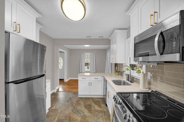 kitchen featuring kitchen peninsula, backsplash, stainless steel appliances, sink, and white cabinetry