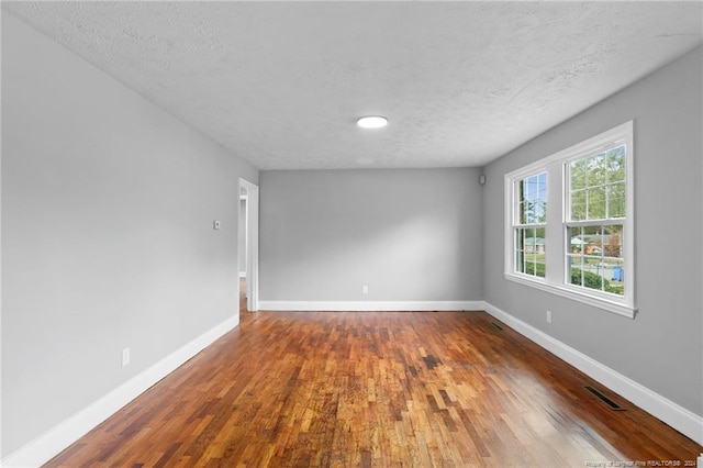 unfurnished room featuring dark hardwood / wood-style flooring and a textured ceiling