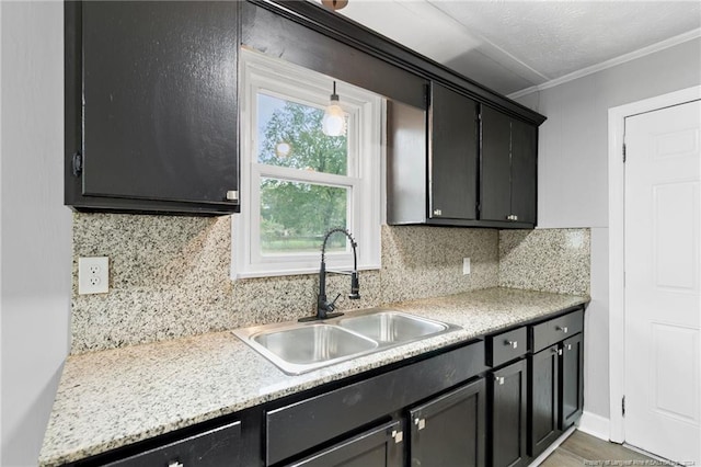 kitchen featuring decorative backsplash, ornamental molding, a textured ceiling, sink, and hanging light fixtures