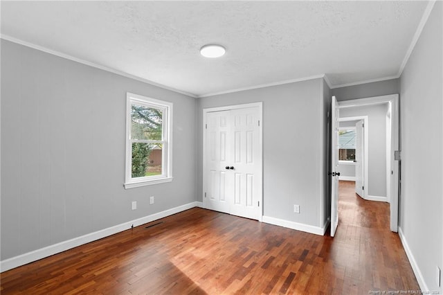 unfurnished bedroom with dark hardwood / wood-style floors, ornamental molding, a textured ceiling, and a closet