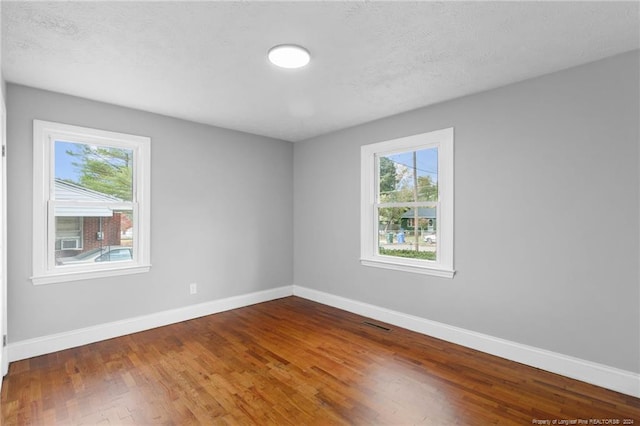 empty room with wood-type flooring and a textured ceiling